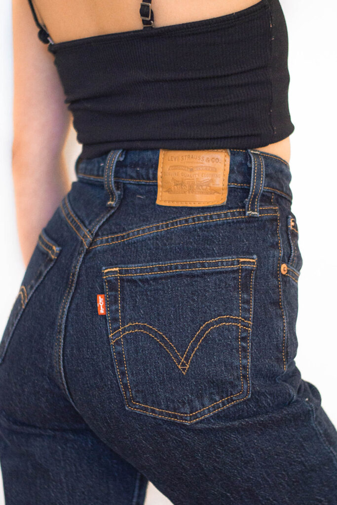 Woman facing opposite direction wearing Levi’s Ribcage Straight Ankle in Dark Stone with back of jeans with Levi's patch and pockets